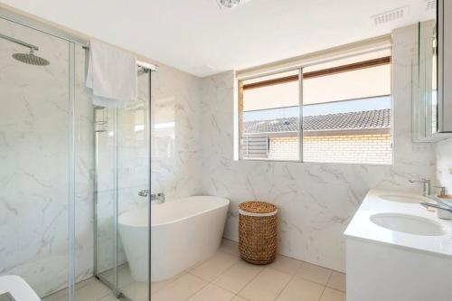a white bathroom with a tub and a sink at Luxe-Coastal Balmoral Townhouse in Sydney
