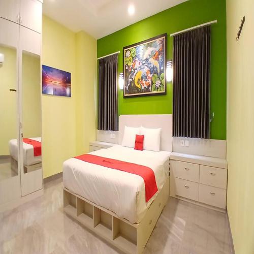a bedroom with a bed and a green wall at RedDoorz at Griya Athaya Maguwoharjo Yogyakarta in Seturan