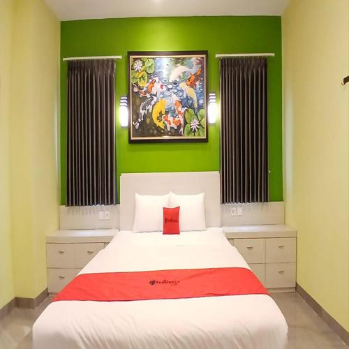 a bedroom with a white bed with green walls at RedDoorz at Griya Athaya Maguwoharjo Yogyakarta in Seturan
