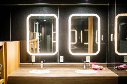 a bathroom with two sinks and three mirrors at Hotel Zipang in Osaka
