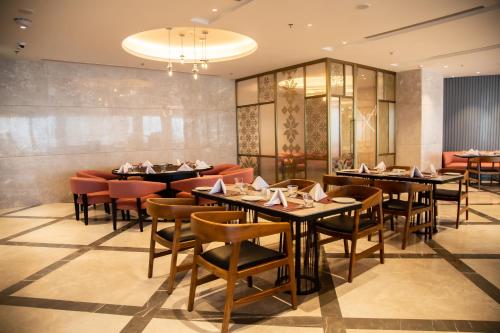 a restaurant with tables and chairs in a room at Sarovar Portico Birgunj in Bīrganj