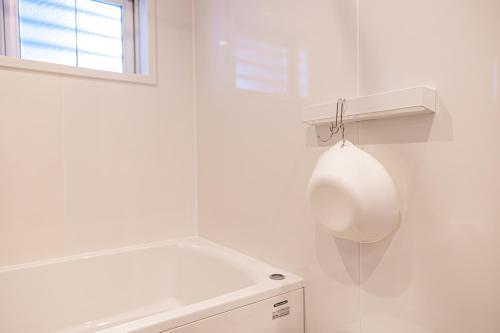 a white bathroom with a white tub and a window at 海の見える高層階グループファミリー歓迎コストコ近くThe琉球タワー9A in Yonabaru