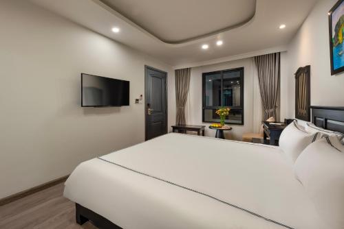 a bedroom with a white bed and a flat screen tv at SQ Hang Gai Hotel & Spa in Hanoi
