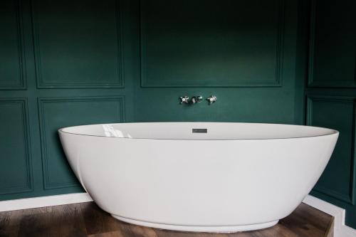 a bath tub in a bathroom with green walls at The Heathcock Boutique Hotel - Room 2 in Cardiff