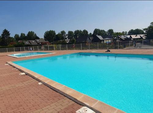 une grande piscine bleue sur une route en briques dans l'établissement Chalet Cabourg California Park, à Cabourg