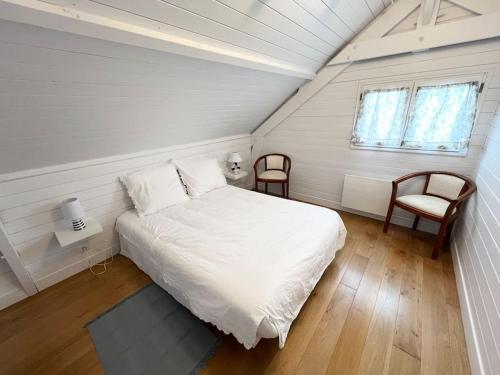 une chambre avec un lit blanc et deux chaises dans l'établissement Chalet Cabourg California Park, à Cabourg