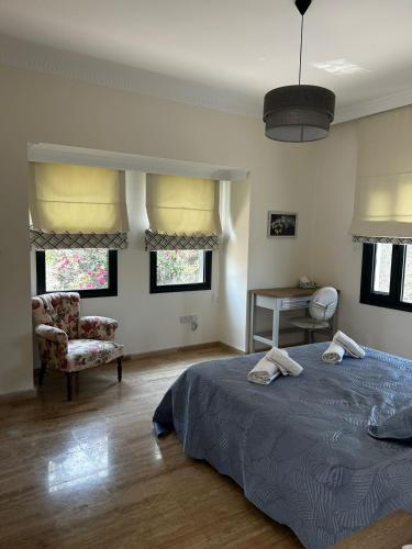 a bedroom with a bed and a chair and windows at Villa Kyrenia in Lapithos
