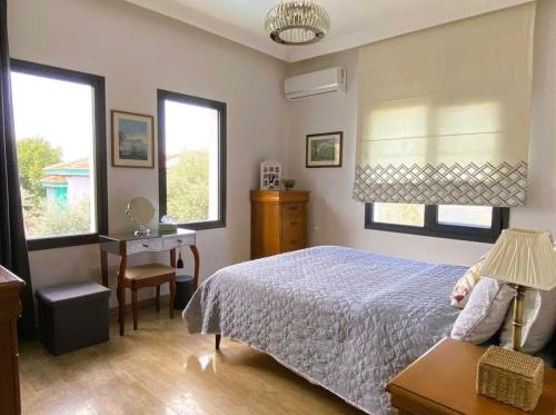 a bedroom with a bed and a desk and two windows at Villa Kyrenia in Lapithos