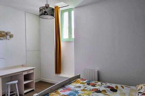 a bedroom with a bed and a desk and a window at Appartement 2 chambres en centre-ville in Parthenay