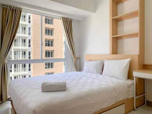 een slaapkamer met een groot bed met een groot raam bij Relaxing 2BR at 35th Floor Tokyo Riverside PIK 2 Apartment By Travelio in Rawalembang