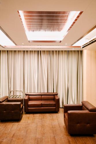 a living room with couches and chairs in front of a curtain at Royal Residence Dhaka in Dhaka