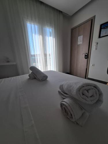 ein Hotelzimmer mit einem Bett, auf dem Handtücher liegen in der Unterkunft Aetherian Suites in Loutra