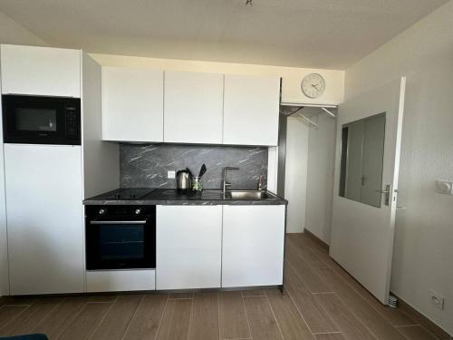 une cuisine avec des armoires blanches et un évier dans l'établissement Appartement vue mer, clim, wifi et parking - 4BEAU418, à Canet