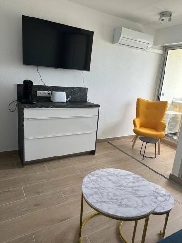 - un salon avec une télévision, une table et une chaise dans l'établissement Appartement vue mer, clim, wifi et parking - 4BEAU418, à Canet