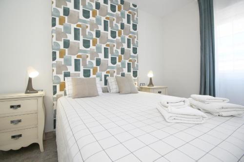 a bedroom with a large white bed with a geometric wall at Del Parque Flats Family Paradise in Rincón de la Victoria
