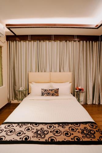 a bedroom with a large white bed with curtains at Royal Residence Dhaka in Dhaka
