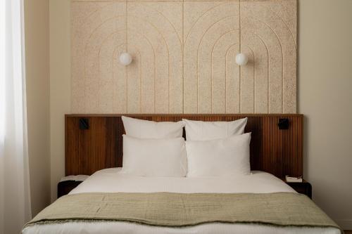 a bed with white pillows and a wooden headboard at Hôtel Fort St Laurent Lyon - Handwritten Collection in Lyon
