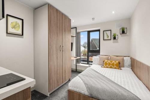 a bedroom with a bed and a cabinet and a window at Stylish Studio Apartment with Free Parking in Wolverhampton 5min walk to City Centre in Wolverhampton
