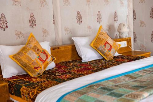 a bedroom with a bed with two pillows on it at Nomads heaven desert camp jaisalmer in Jaisalmer
