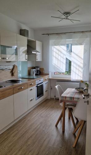 a kitchen with white cabinets and a table and a ceiling at Ferienwohnung Sendelbeck in Warmensteinach