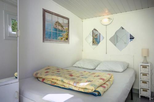 ein weißes Schlafzimmer mit einem Bett mit einer Decke darauf in der Unterkunft Studio piscine partagée in Brétignolles-sur-Mer