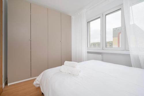 ein weißes Schlafzimmer mit einem weißen Bett und zwei Fenstern in der Unterkunft Górna Pleasant Apartment in Rokicie