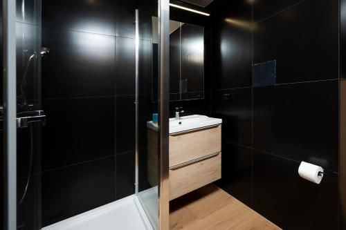 ein schwarzes Badezimmer mit Waschbecken und Dusche in der Unterkunft Górna Pleasant Apartment in Rokicie