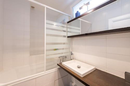 une salle de bain blanche avec un lavabo et un miroir dans l'établissement Geranimus Parisian Charm, à Paris