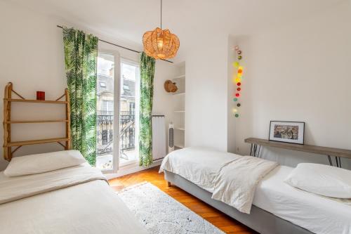 une chambre avec deux lits et une fenêtre dans l'établissement Geranimus Parisian Charm, à Paris