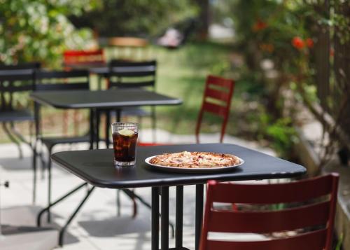 a pizza on a table with a glass of soda at ibis Lyon Carre De Soie in Vaulx-en-Velin