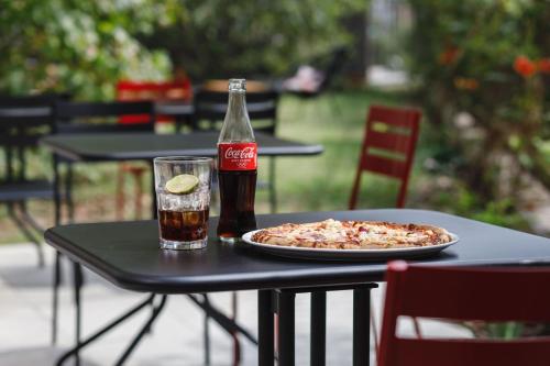 a bottle of soda and a pizza on a table at ibis Lyon Carre De Soie in Vaulx-en-Velin