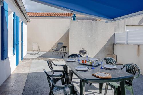 une table et des chaises bleues sur une terrasse dans l'établissement Maison proche océan - 6 pers, à Bretignolles-sur-Mer