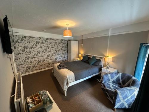 a bedroom with a bed and a chair at The Black Horse Inn in Dursley