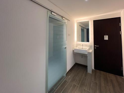a bathroom with a glass shower and a sink at Box City Hotel Mojokerto in Mojokerto