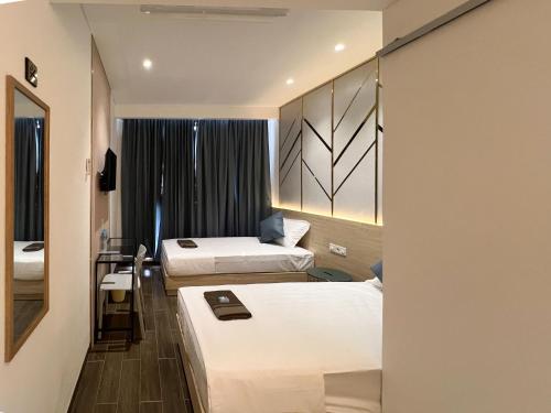 a hotel room with two beds and a mirror at Box City Hotel Mojokerto in Mojokerto