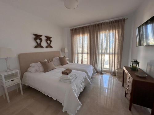a white bedroom with a bed and a window at Apartamento Puerto Sotogrande in Sotogrande