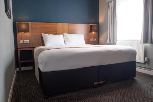 a bedroom with a large bed with a wooden headboard at The White Hart by Innkeeper's Collection in Hook