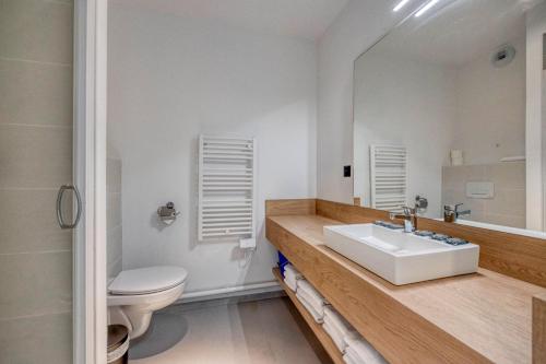 a bathroom with a sink and a toilet and a mirror at KOSY APPART'HÔTELS - Résidence du Lac in Aix-les-Bains