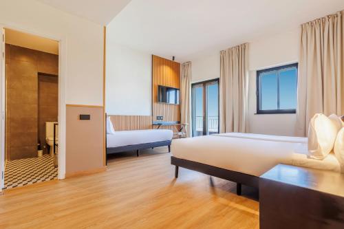 a hotel room with two beds and a bathroom at Hotel Acta Madfor in Madrid