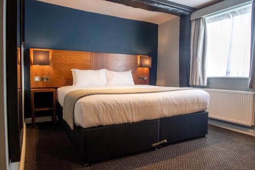 a bedroom with a large bed with a blue wall at The White Hart by Innkeeper's Collection in Hook