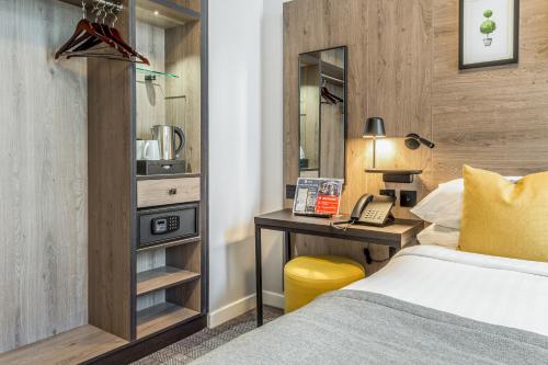 Una habitación de hotel con una cama y un escritorio con teléfono. en Princes Square, en Londres