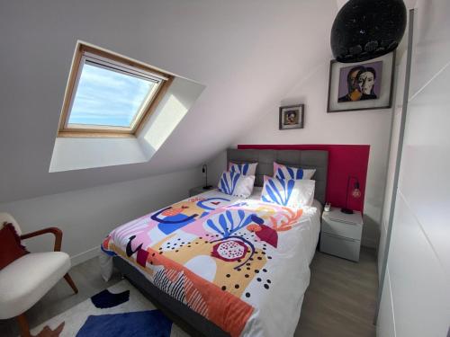 une chambre avec un lit avec une couette colorée et une fenêtre dans l'établissement Le Roule, à Cherbourg en Cotentin