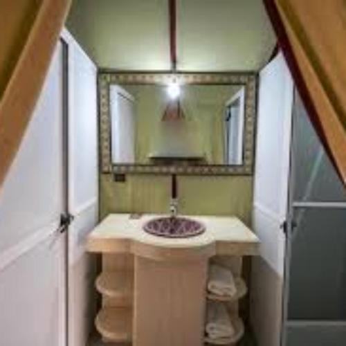a bathroom with a sink and a mirror at Aaladdin luxury camp in Merzouga