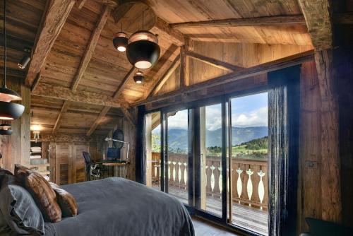 - une chambre avec une grande fenêtre offrant une vue sur la montagne dans l'établissement CHALET LES CERISES Jacuzzi, Sauna, Hammam, Cinéma, à Cordon