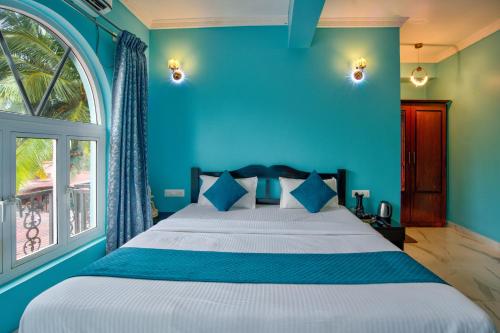 a blue bedroom with a bed and a window at Candolim Beach White Residency in Baga