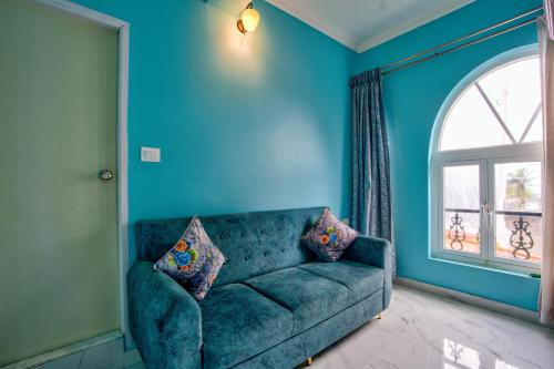 a blue living room with a couch and a window at Candolim Beach White Residency in Baga
