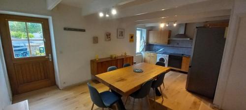 a kitchen with a wooden table and chairs and a refrigerator at Charmante maison de pêcheur in Carantec