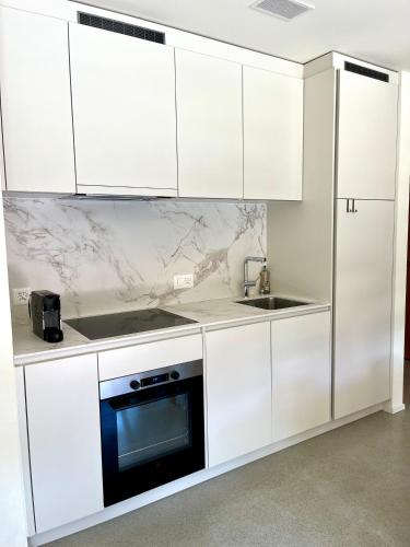 a white kitchen with white cabinets and a sink at Ferienwohnung Stenna SELVA direkt bei Bergbahnen Skipiste in Flims