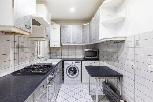 une cuisine avec des armoires blanches et une laveuse et une sécheuse dans l'établissement GuestReady - Apt Lumineux près de la Gare de l'Est, à Paris