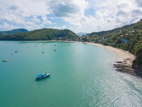 a boat in a body of water next to a beach at At the Beach New comfortable Pool Home, Ao Yon Beach, Phuket in Ban Ao Makham